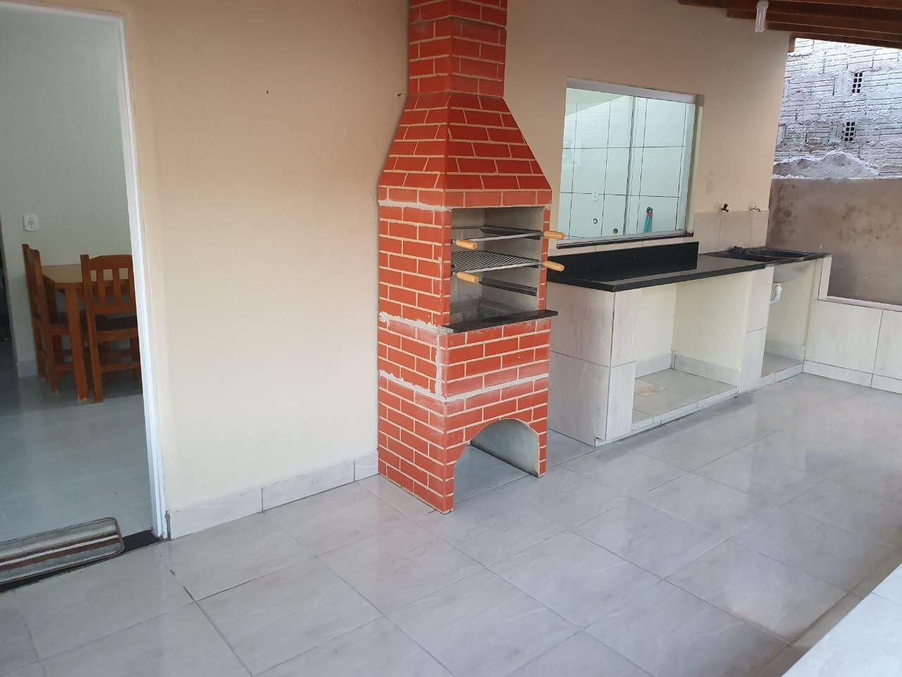 Outdoor kitchen with red brick grill and countertop next to a small dining area.