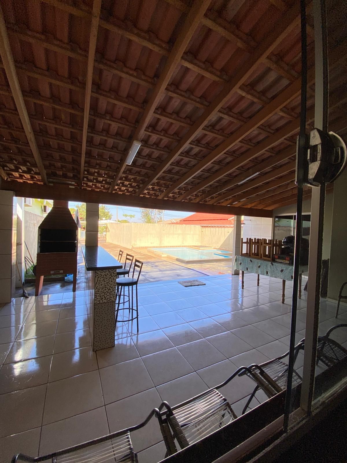 Covered patio with tiled floor, bar, chairs, and view of pool outside.